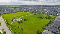 Expansive green space featuring recreational fields, paved walking paths, a dedicated playground area, and mature trees - 