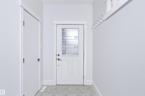 Entryway featuring a white paneled door with patterned privacy glass, alongside a secondary white door with horizontal paneling - 1235 164 Street, Edmonton, AB 