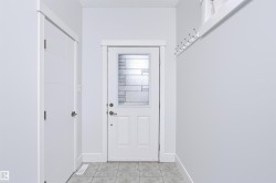 Entryway featuring a white paneled door with patterned privacy glass, alongside a secondary white door with horizontal paneling - 