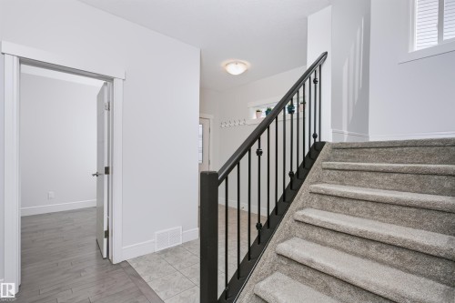 Carpeted staircase featuring a black metal balustrade and wood handrail - 1235 164 Street, Edmonton, AB 