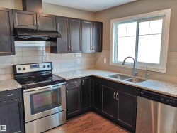 Kitchen featuring dark wood-finish cabinetry, speckled countertops, and a white tile backsplash - 