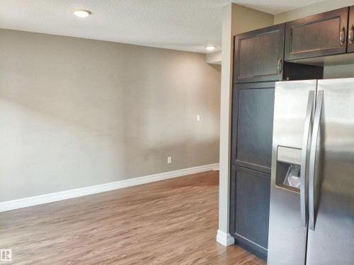 Stainless steel refrigerator integrated with dark wood-finish cabinetry - 23 1508 105 Street, Edmonton, AB 