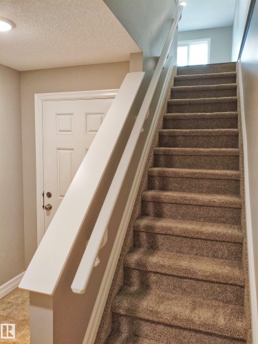 Carpeted staircase with white handrail and trim - 23 1508 105 Street, Edmonton, AB 