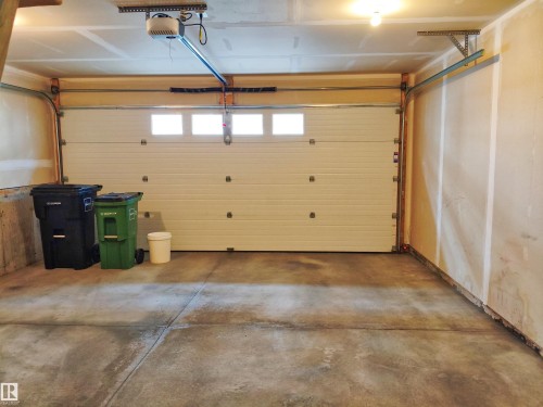 Single-car garage featuring a sectional overhead door with integrated windows and an automatic opener system - 23 1508 105 Street, Edmonton, AB 