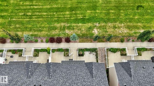 Private patios featuring concrete surfacing and perimeter landscaping, bordering a public sidewalk and expansive green space - #23 1508 105 St Nw, Edmonton, AB - Outdoor
