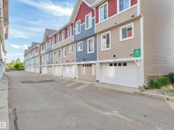 Row of townhomes featuring multi-colored siding, individual garage doors, white window trim, and gabled rooflines - 