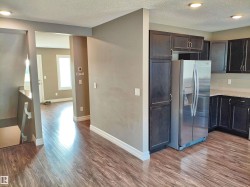 Open-concept kitchen featuring dark wood cabinetry, stainless steel refrigerator, and light-toned countertops - 