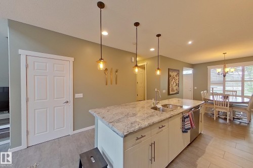 Kitchen island featuring a double basin sink, stainless steel dishwasher, and stone countertop - 14412 98 Street, Edmonton, AB - Indoor Photo Showing Kitchen With Double Sink