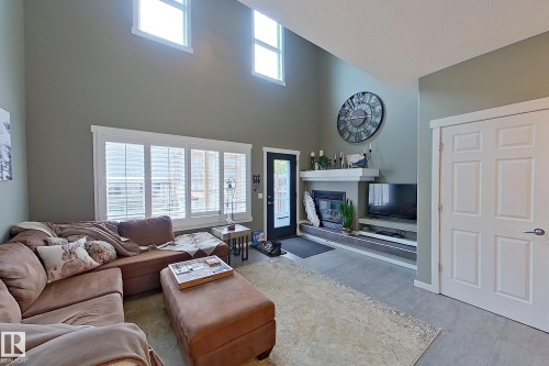 Living area featuring vaulted ceilings, a fireplace with a mantel, and built-in shelving - 14412 98 Street, Edmonton, AB - Indoor With Fireplace