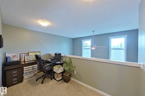 Versatile loft space featuring wood-finish flooring and a white half-wall railing - 14412 98 Street, Edmonton, AB - Indoor