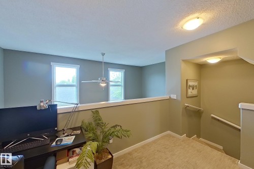 Open loft area featuring a ceiling fan, two windows, and textured carpeting - 14412 98 Street, Edmonton, AB - Indoor Photo Showing Other Room