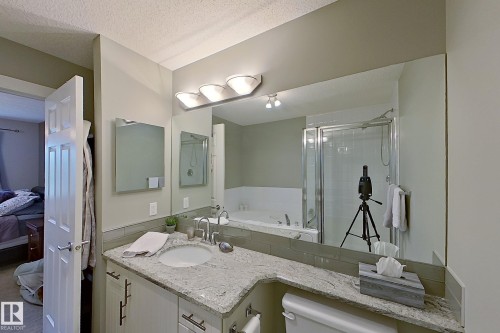 Bathroom vanity featuring a polished stone countertop with an integrated sink and modern brushed nickel fixtures - 14412 98 Street, Edmonton, AB - Indoor Photo Showing Bathroom