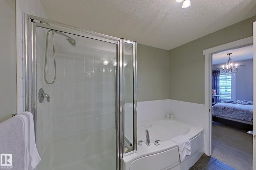 Bathroom featuring a glass-enclosed shower, a corner built-in bathtub with deck-mounted fixtures, half-height white tiled walls, and a light-toned wall color - 14412 98 Street, Edmonton, AB - Indoor Photo Showing Bathroom