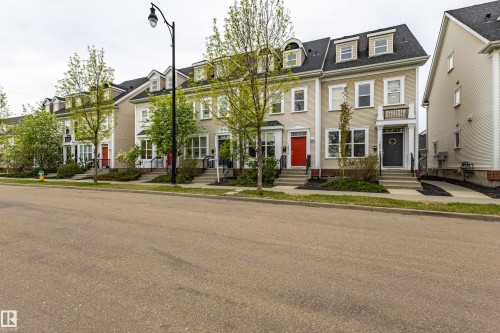 Traditional townhome exterior featuring light-colored siding, contrasting dark roof, and multiple dormer windows - 14412 98 Street, Edmonton, AB - Outdoor With Facade