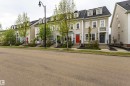 Traditional townhome exterior featuring light-colored siding, contrasting dark roof, and multiple dormer windows - 14412 98 Street, Edmonton, AB  - Outdoor With Facade 