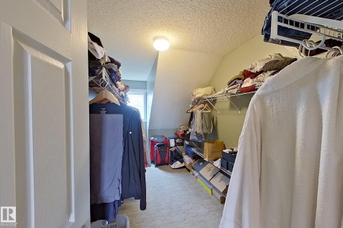 Walk-in closet featuring sloped ceilings, carpet flooring, a window, and extensive wire shelving - 14412 98 Street, Edmonton, AB - Indoor With Storage
