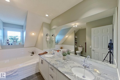 Bathroom featuring a built-in tub, dual sink vanity with granite countertop, and white cabinetry - 14412 98 Street, Edmonton, AB - Indoor Photo Showing Bathroom
