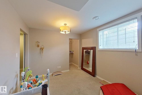 Carpeted room featuring a ceiling-mounted light fixture, recessed lighting, a window with blinds, and an open doorway leading to a walk-in closet - 14412 98 Street, Edmonton, AB - Indoor