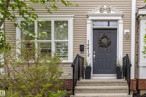 Inviting front entry featuring a paneled door, decorative door surround, transomed window, and stone steps with wrought iron railings - 14412 98 Street, Edmonton, AB - Outdoor With Facade