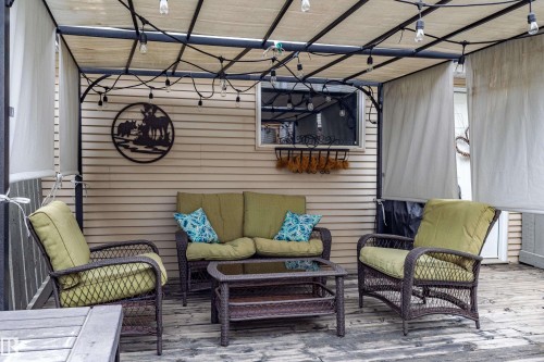 Covered outdoor patio with a fabric canopy, string lighting, and wood-finish decking - 14412 98 Street, Edmonton, AB - Outdoor With Deck Patio Veranda With Exterior