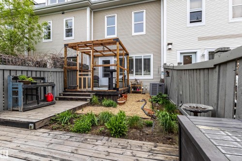 Private outdoor space featuring a wood pergola structure, multi-level wood decking, gravel landscaping, planted garden beds, and vertical fencing - 14412 98 Street, Edmonton, AB - Outdoor With Deck Patio Veranda With Exterior
