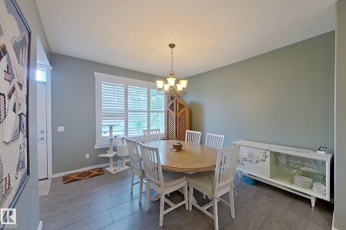 Dining area featuring wood-finish flooring, a contemporary chandelier, and a window with plantation shutters - 14412 98 Street, Edmonton, AB - Indoor Photo Showing Dining Room