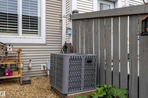 Exterior featuring light-colored siding, a white-trimmed window with blinds, and a gravel-covered ground surface - 14412 98 Street, Edmonton, AB - Outdoor