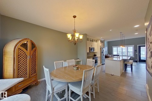 Open-concept living space featuring wood-finish flooring, a kitchen island with seating, pendant lighting, stainless steel appliances, and white cabinetry - 14412 98 Street, Edmonton, AB - Indoor Photo Showing Dining Room