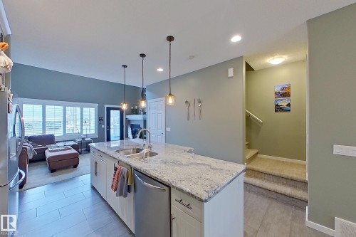 Kitchen island with integrated sink, stainless steel dishwasher, and pendant lighting - 14412 98 Street, Edmonton, AB - Indoor Photo Showing Kitchen With Double Sink