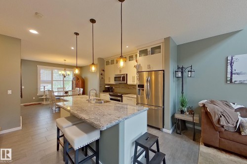 Kitchen with a granite-top island featuring a stainless steel sink and pendant lighting - 14412 98 Street, Edmonton, AB - Indoor Photo Showing Kitchen