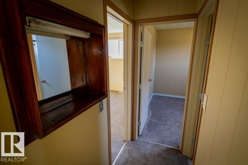 Hallway featuring light-toned paneling, dark wood-finish trim, and carpet flooring - 5218 52 Ave, St. Paul Town, AB - Indoor Photo Showing Other Room