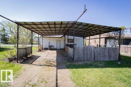Carport structure with a metal roof, concrete slab, and adjacent wooden fencing - 5218 52 Ave, St. Paul Town, AB - Outdoor