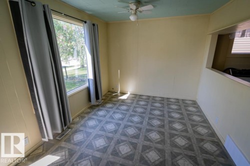 Spacious room featuring patterned flooring, a window offering exterior views, and a ceiling fan with integrated lighting - 5218 52 Ave, St. Paul Town, AB - Indoor