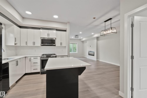 Modern kitchen featuring white glossy cabinetry, quartz countertops, a stainless steel gas range, and an integrated microwave - 383 Charlesworth Drive, Edmonton, AB 