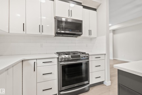 Modern kitchen featuring white cabinetry, subway tile backsplash, stainless steel gas range, over-the-range microwave, and light-toned flooring - 383 Charlesworth Drive, Edmonton, AB 