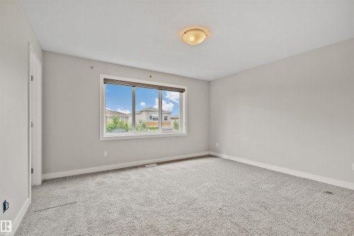 Spacious room featuring light gray walls, white trim, and light gray carpeted flooring - 383 Charlesworth Drive, Edmonton, AB 