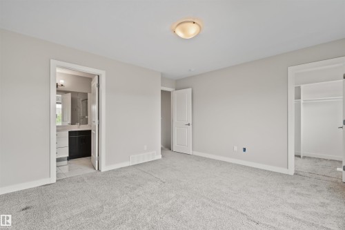Spacious room featuring light gray carpeting, white baseboards, and a semi-flush mount ceiling light - 383 Charlesworth Drive, Edmonton, AB 