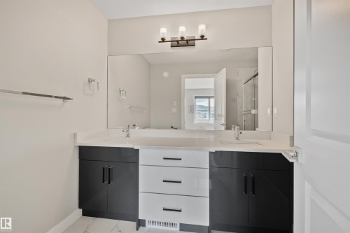 Dual vanity featuring white countertops, two integrated sinks, and contemporary two-tone cabinetry with both black and white finishes - 383 Charlesworth Drive, Edmonton, AB 