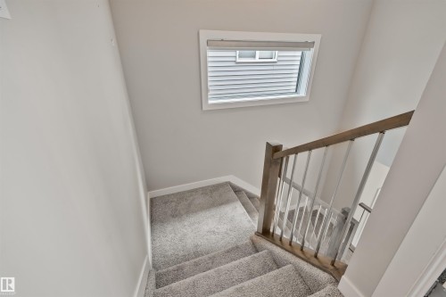 Carpeted staircase featuring a wood-finish handrail with metal balusters - 383 Charlesworth Drive, Edmonton, AB 