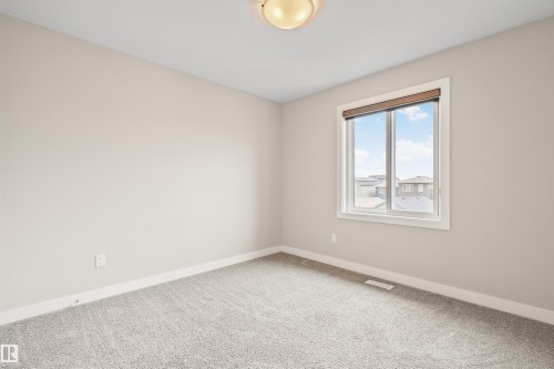 Room featuring a large window with a brown blind, light gray carpet, and neutral-toned walls - 383 Charlesworth Drive, Edmonton, AB 