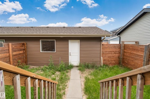Brown horizontal siding structure with a white door and window, featuring a brown shingle roof and light brown gutters - 383 Charlesworth Drive, Edmonton, AB 
