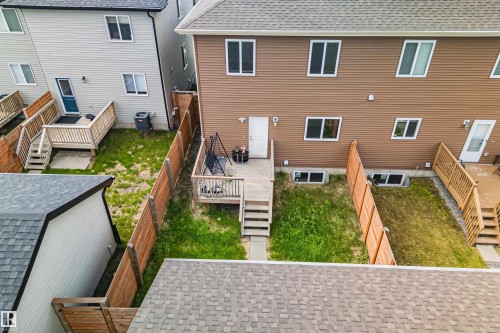 Rear exterior featuring brown horizontal siding, multiple windows with white trim, and a private wooden deck with stairs - 383 Charlesworth Drive, Edmonton, AB 