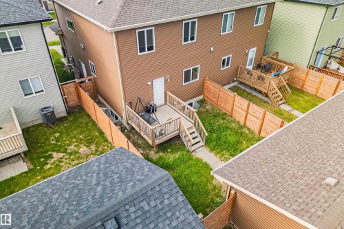 Rear exterior featuring a brown siding facade, a multi-level wood deck, a private fenced yard, and white-framed windows - 383 Charlesworth Drive, Edmonton, AB 