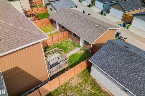Fenced backyard featuring a wood-finish deck with railings, a concrete walkway, and a landscaped lawn area - 383 Charlesworth Drive, Edmonton, AB 
