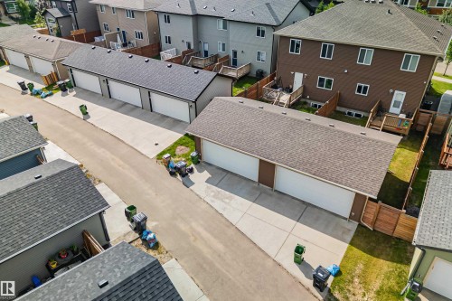 Rear-entry multi-stall garage with individual doors, shingle roofing, and concrete driveways - 383 Charlesworth Drive, Edmonton, AB 