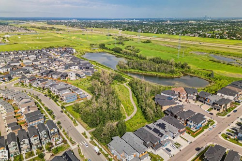 Expansive residential area featuring a mix of single-family homes and townhomes with dark shingle roofs, surrounded by green spaces, natural ponds, and walking paths - 383 Charlesworth Drive, Edmonton, AB 