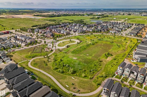 Expansive green space featuring meandering paved pathways, mature trees, and community garden plots - 383 Charlesworth Drive, Edmonton, AB 