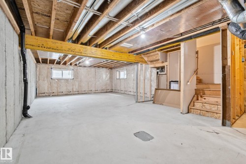 Unfinished lower level featuring exposed framing, concrete flooring, two windows, and an unfinished staircase - 383 Charlesworth Drive, Edmonton, AB 