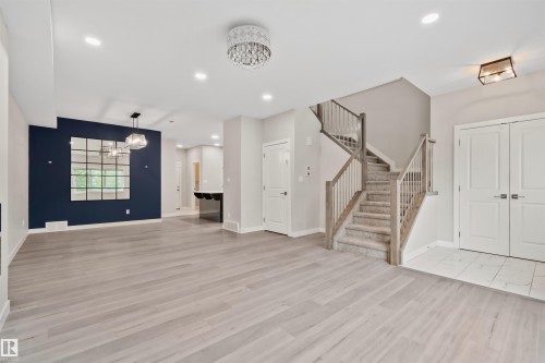 Open-concept living area featuring light wood-finish flooring, a contemporary crystal chandelier, and recessed lighting - 383 Charlesworth Drive, Edmonton, AB 