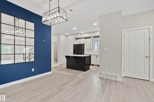 Open-concept living space with light wood-finish flooring, a modern geometric chandelier, and recessed lighting - 383 Charlesworth Drive, Edmonton, AB 